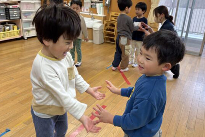 室内でリズムに合わせて手拍子や手遊びをする2人の男の子